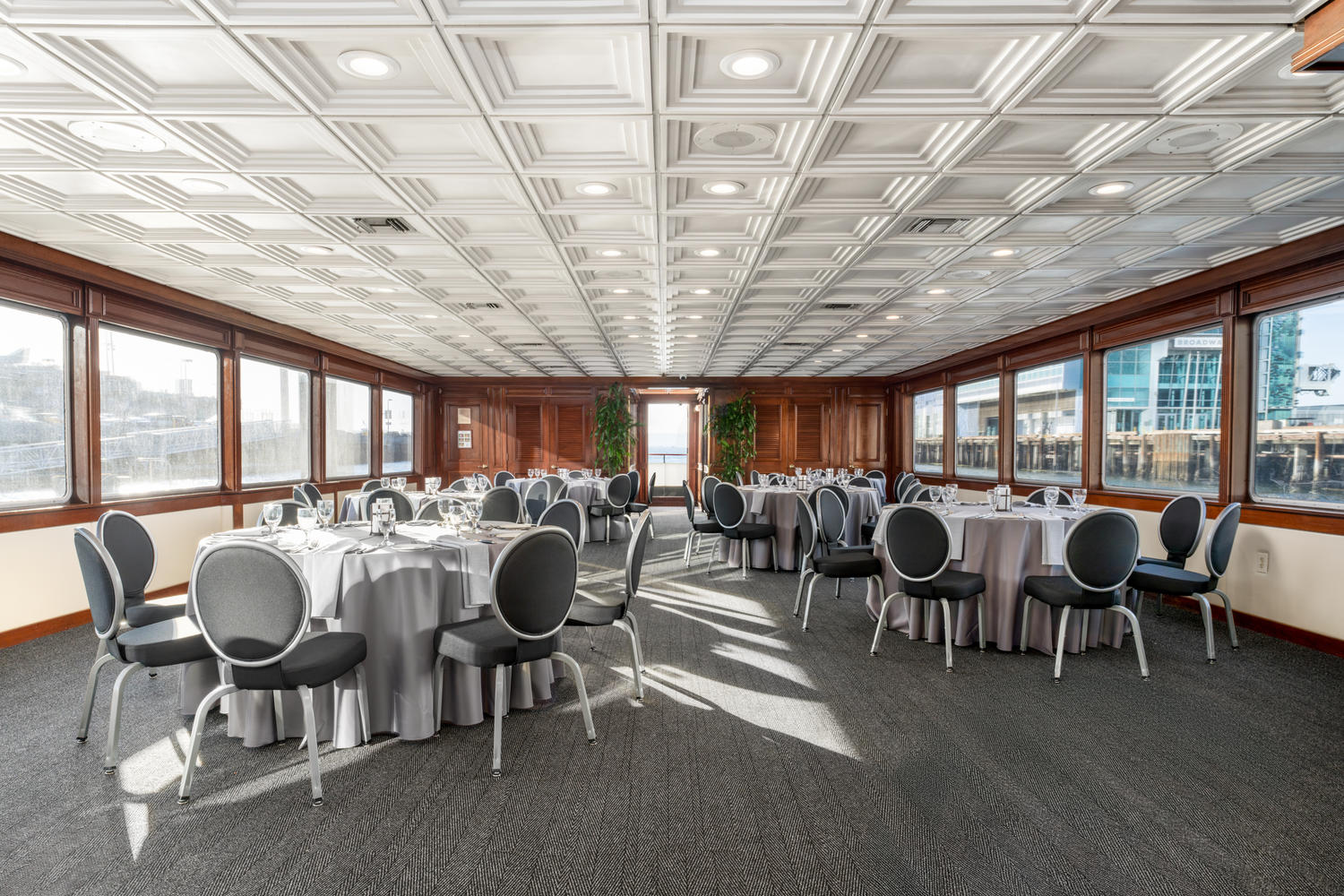 Main Deck – Aft View | Dining room set for dinner with water and city views.