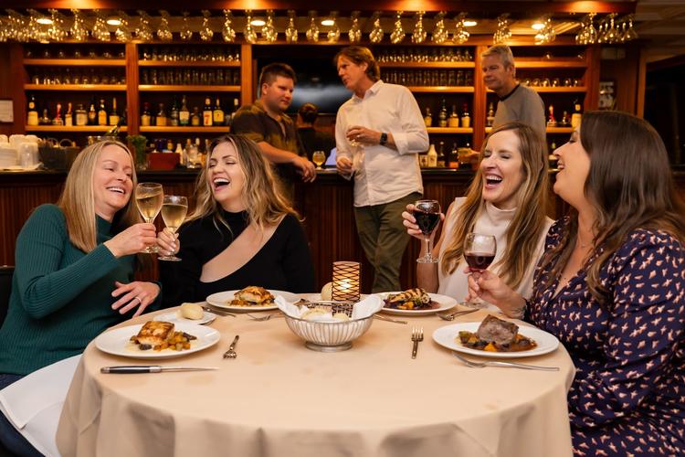 Guests enjoy a seated dinner and wine during rehearsal dinner cruise