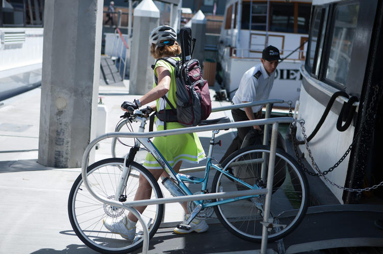 Person in bright clothing walking a bicycle up a ramp on Bike Anywhere Day
